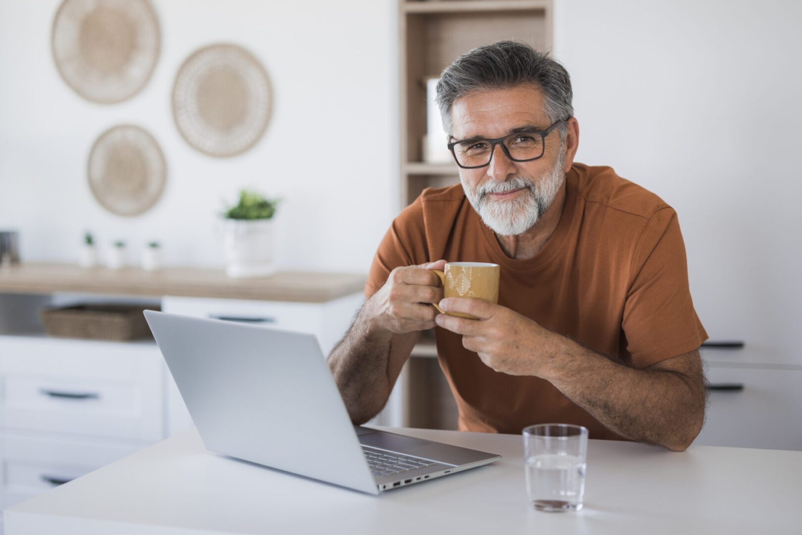 Man drinking coffee while using a laptop.