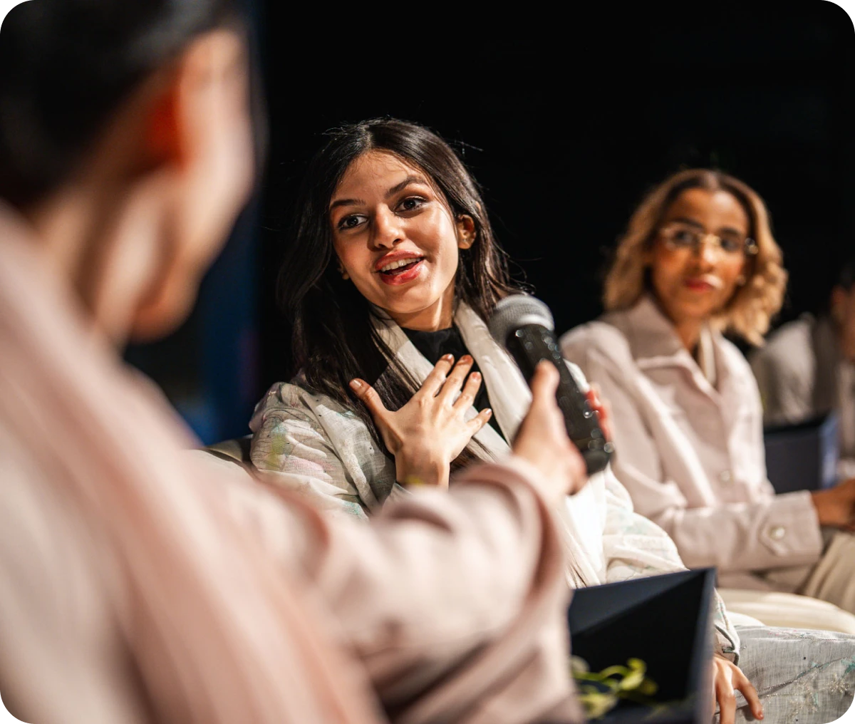 Woman speaking on panel with microphone.