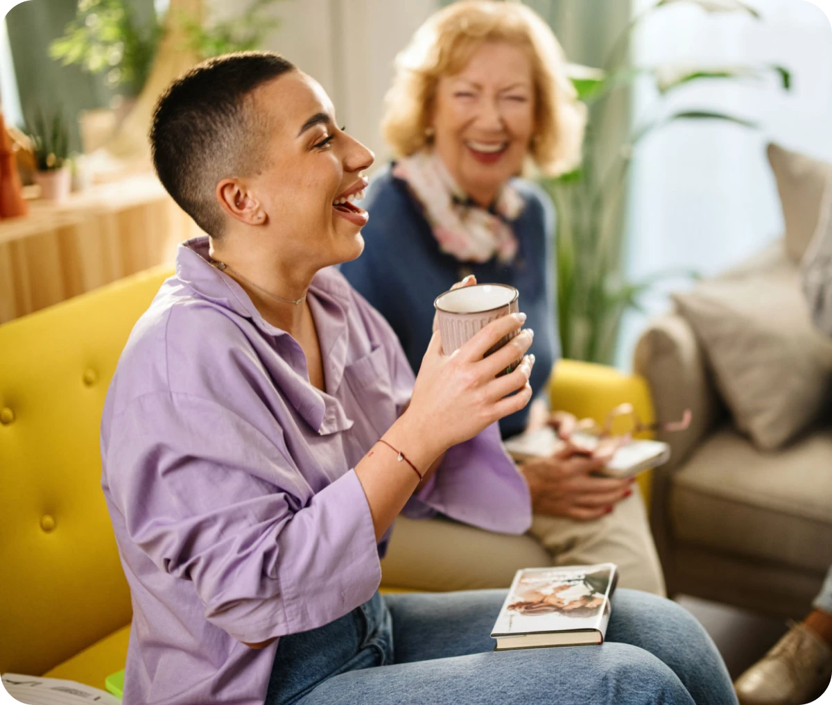 Two people laughing on a yellow couch.